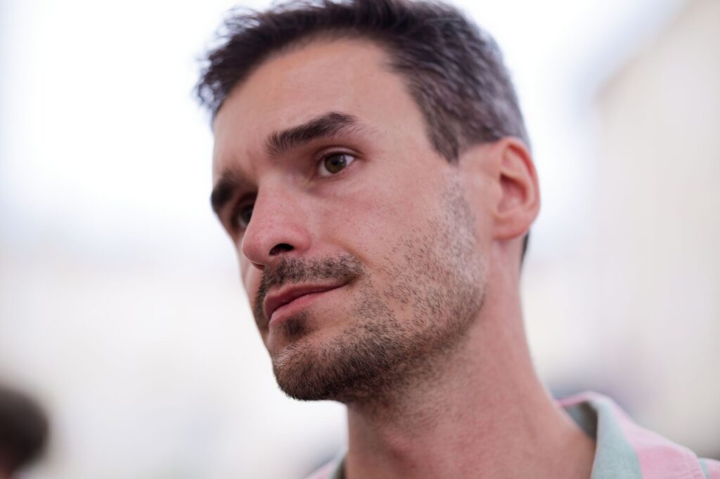 Un portrait en gros plan d'un homme avec une expression réfléchie, mettant en valeur un arrière-plan flou.