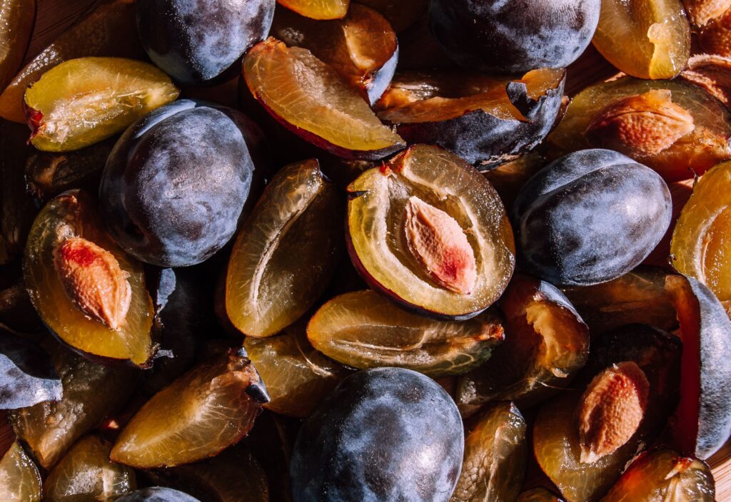 Gros plan éclatant de prunes mûres coupées en deux, mettant en valeur leurs couleurs et textures riches.