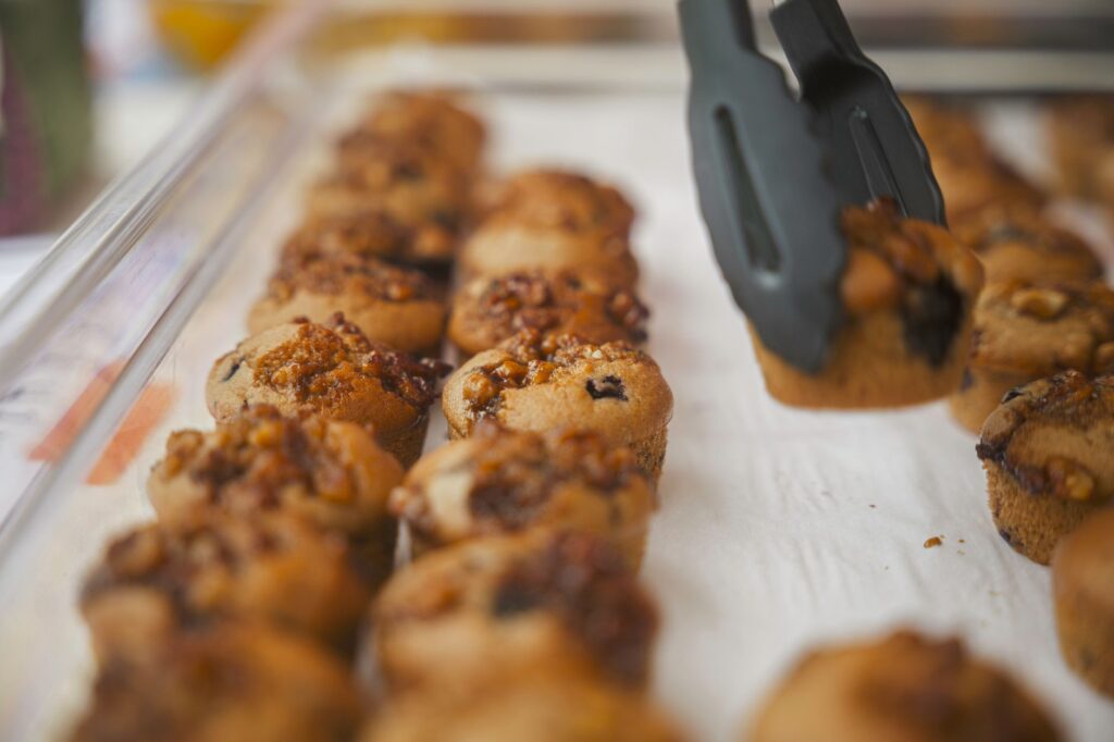 Gros plan sur des muffins fraîchement sortis du four, garnis de noix et de baies, disposés sur un plateau.