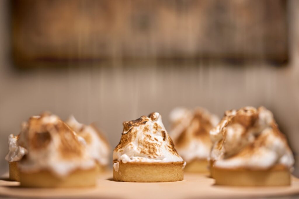 Gros plan sur des tartelettes au citron meringuées dorées, mettant en valeur leurs pointes de meringue grillées.