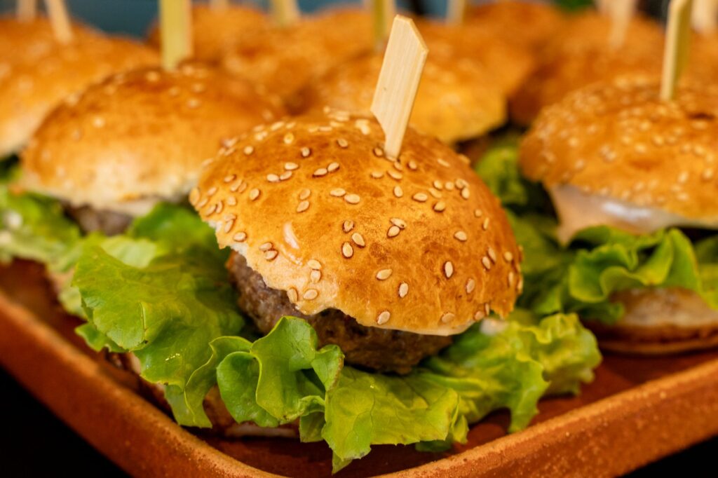 De délicieux mini-hamburgers avec de la laitue, présentés sur un plateau. Parfaits pour les fêtes ou les repas décontractés.