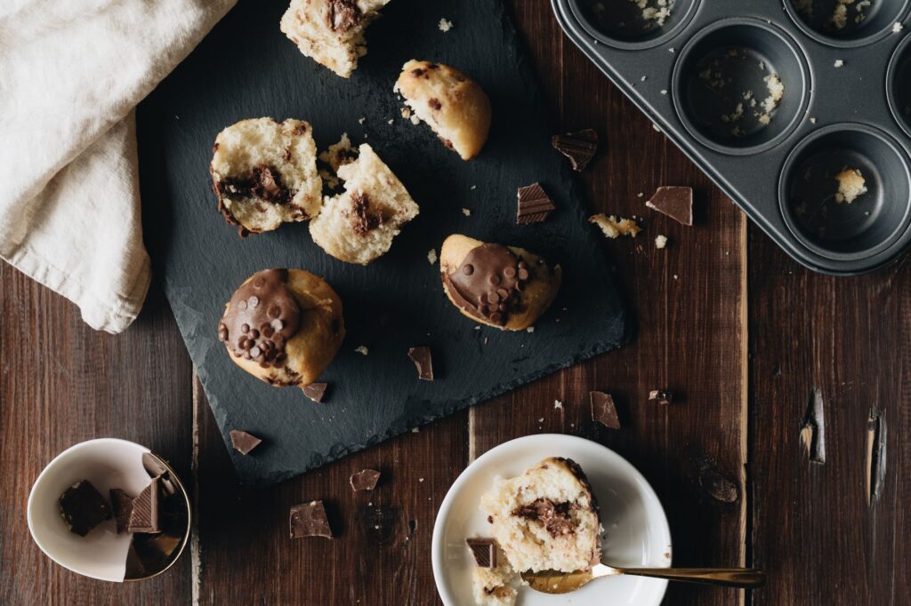 Muffins aux pépites de chocolat fraîchement cuits sur une table en bois rustique, parfaits pour les desserts.