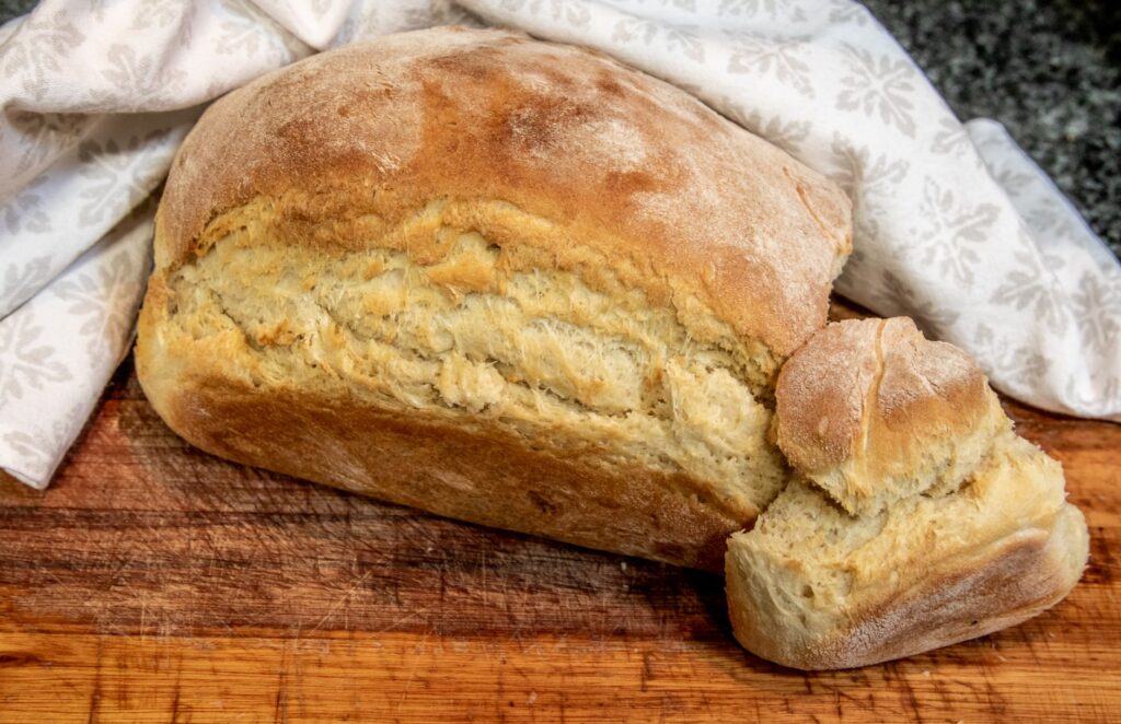 Délicieuse miche de pain maison avec une croûte croustillante sur une planche en bois, parfaite pour les présentations culinaires.
