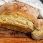 Délicieuse miche de pain maison avec une croûte croustillante sur une planche en bois, parfaite pour les présentations culinaires.