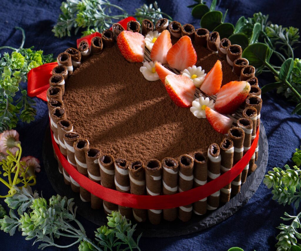 Délicieux gâteau au chocolat décoré de fraises et d'accents floraux sur un fond sombre.