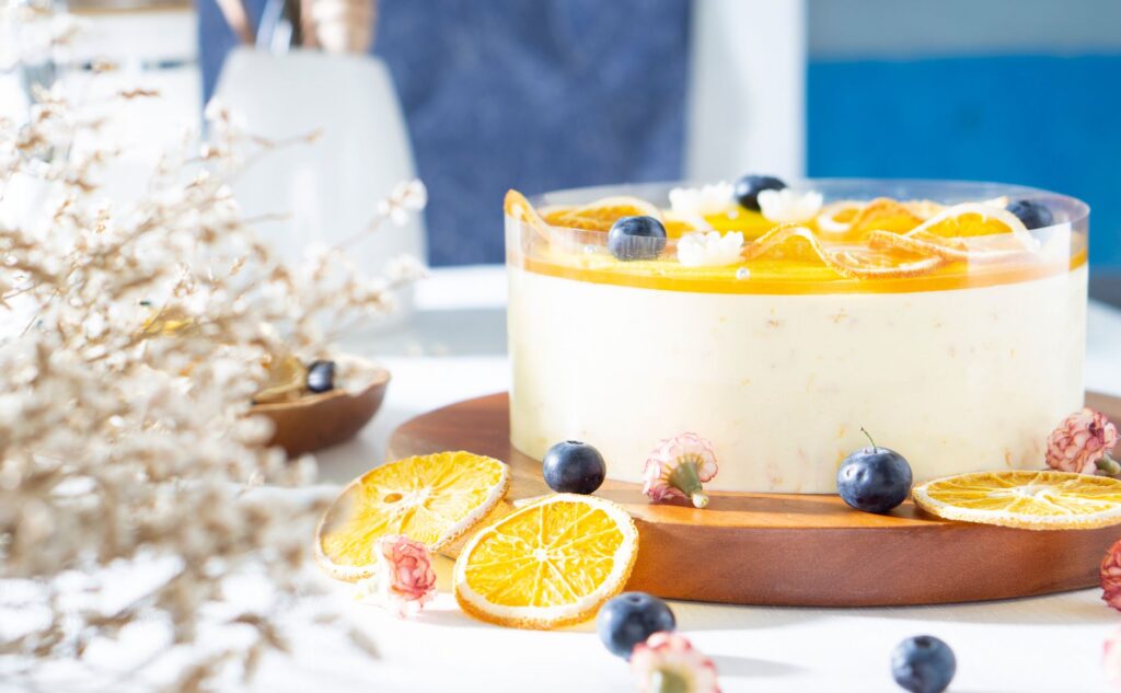 Un gâteau au fromage orange irrésistible garni de myrtilles et d'oranges séchées, parfait pour les amateurs de desserts.