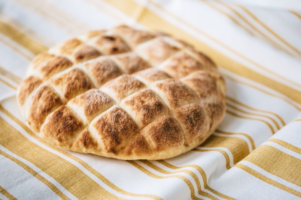 Pain rustique fraîchement cuit posé sur un tissu en lin rayé, mettant en valeur la texture et la croûte.