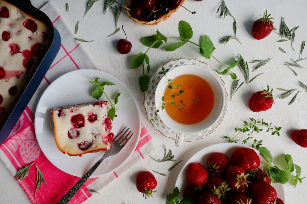 Délicieux gâteau aux cerises servi avec des fraises fraîches et une tasse de thé aux herbes. Vue de dessus.