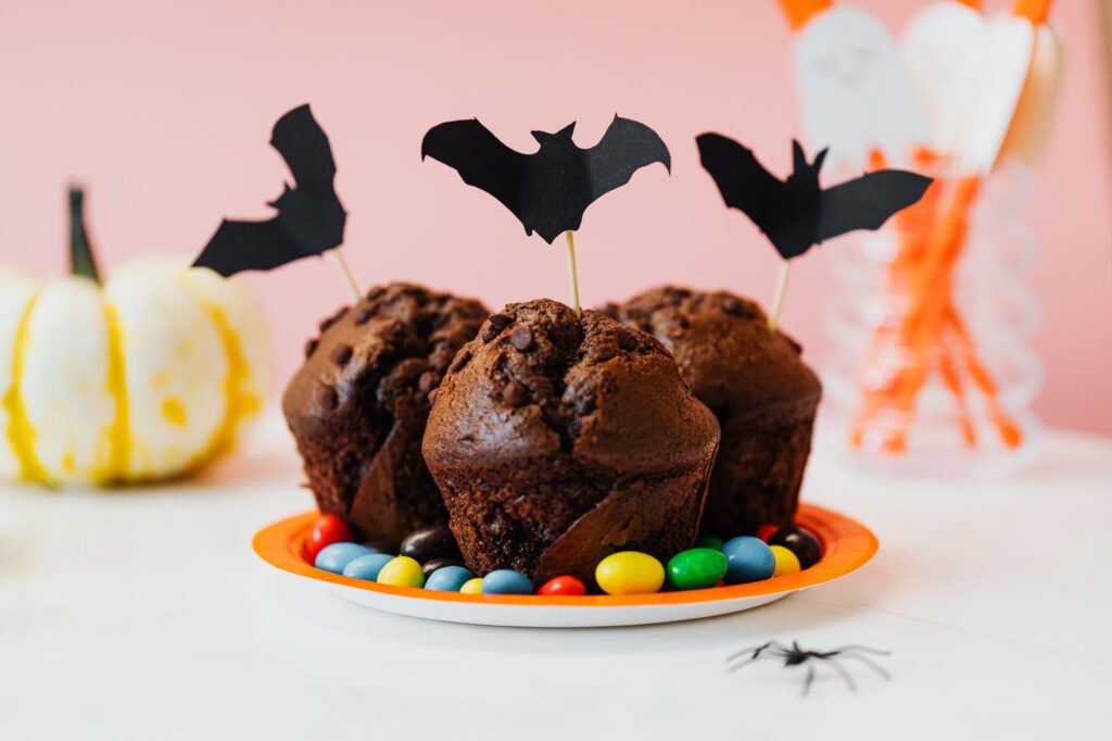 Délicieux cupcakes au chocolat avec des décorations de chauve-souris et des bonbons sur un fond à thème Halloween.