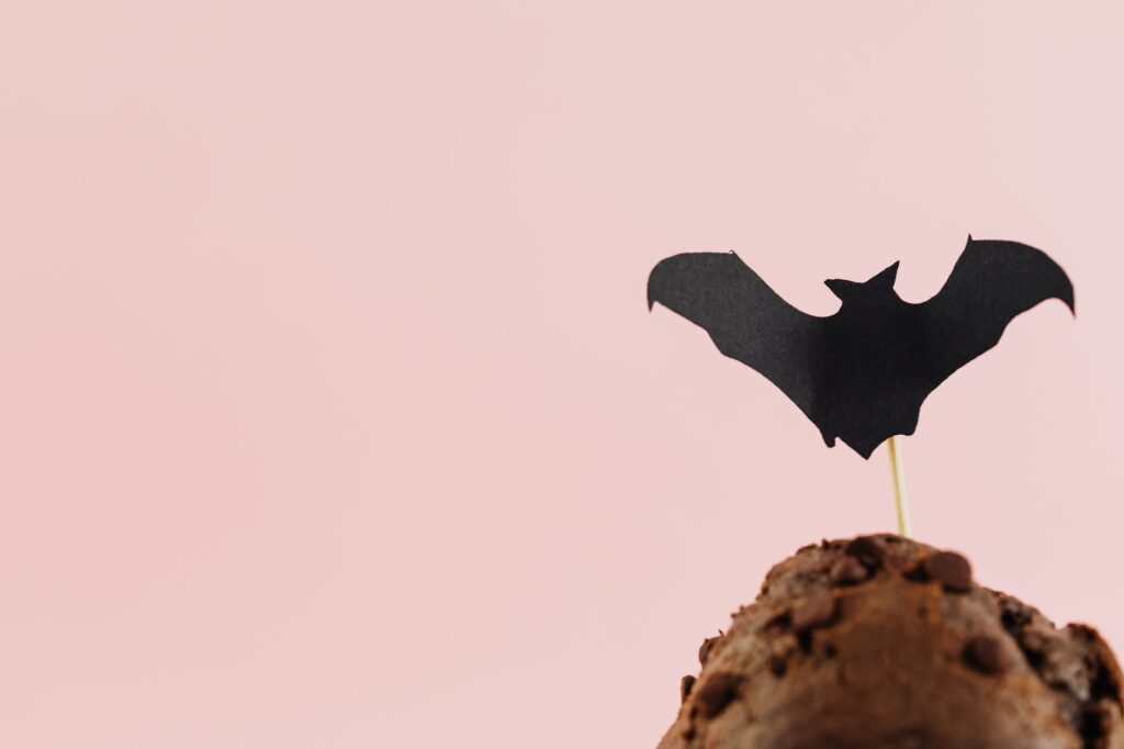 Gros plan sur un muffin au chocolat avec une décoration de chauve-souris sur le dessus, parfait pour des thèmes d'Halloween.