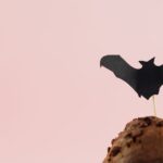 Gros plan sur un muffin au chocolat avec une décoration de chauve-souris sur le dessus, parfait pour des thèmes d'Halloween.