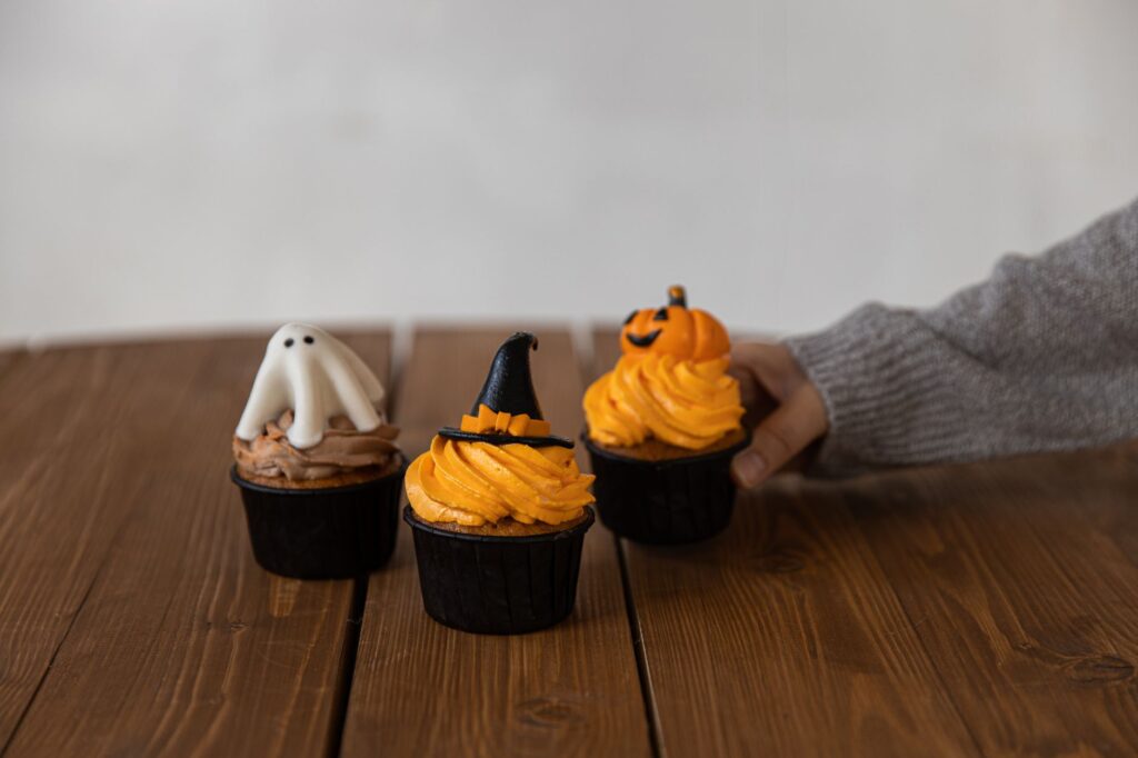 Cupcakes sur le thème d'Halloween décorés avec des fantômes, des chapeaux de sorcière et des citrouilles, parfaits pour des desserts festifs.