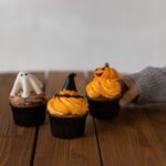 Cupcakes sur le thème d'Halloween décorés avec des fantômes, des chapeaux de sorcière et des citrouilles, parfaits pour des desserts festifs.