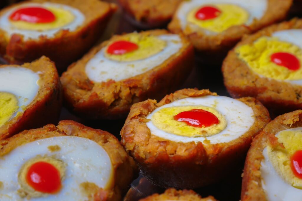 Délicieux œufs écossais garnis de poivrons colorés, idéaux pour la photographie culinaire et l'inspiration de repas.