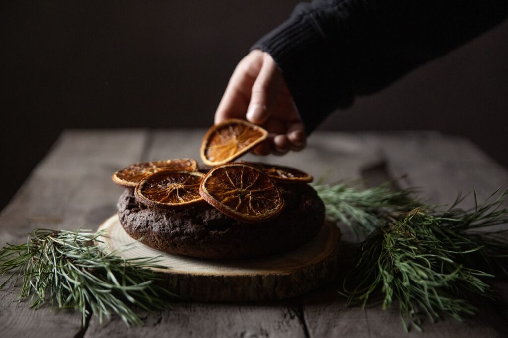 Décoration à la main d'un gâteau au chocolat avec des tranches d'orange séchées sur une table en bois rustique.