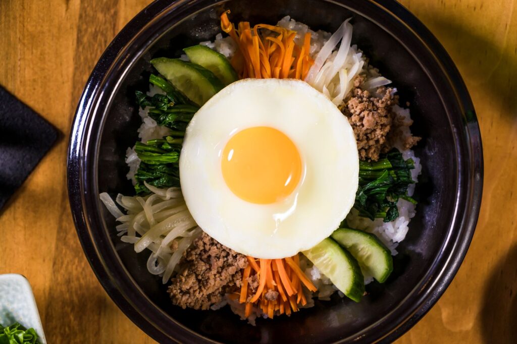 Bibimbap coréen coloré avec des légumes et un œuf au plat.
