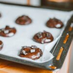 Des cookies aux pépites de chocolat fraîchement cuits refroidissent sur une plaque de cuisson. Parfait pour les amateurs de dessert.