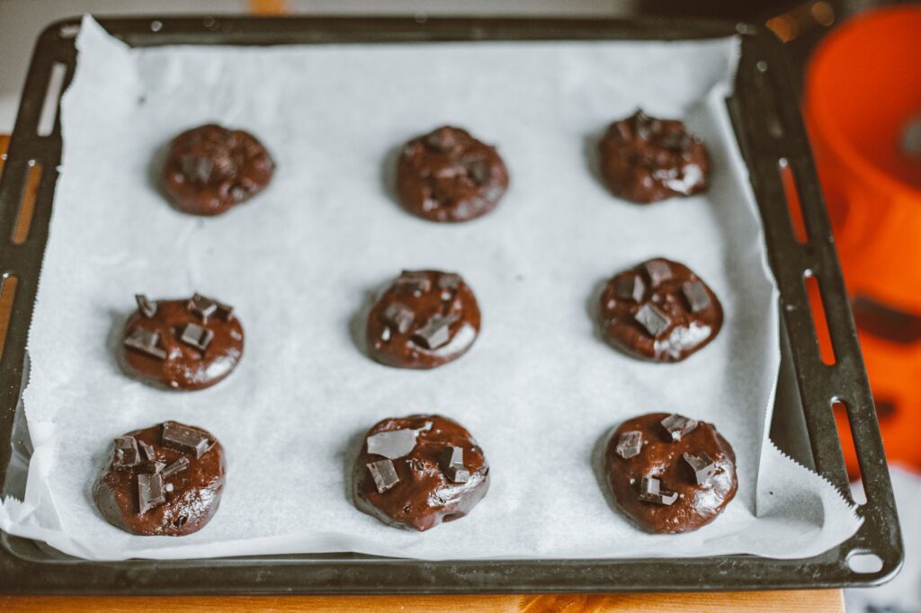 Délicieuses cookies au chocolat maison sur une plaque de cuisson tapissée de papier parchemin, prêtes à être cuites.