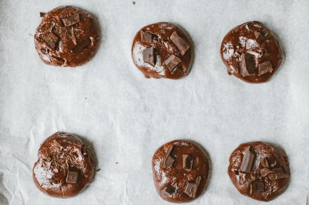 Vue du dessus des biscuits au chocolat avec des morceaux sur une plaque de cuisson.