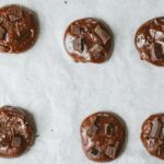 Vue du dessus des biscuits au chocolat avec des morceaux sur une plaque de cuisson.