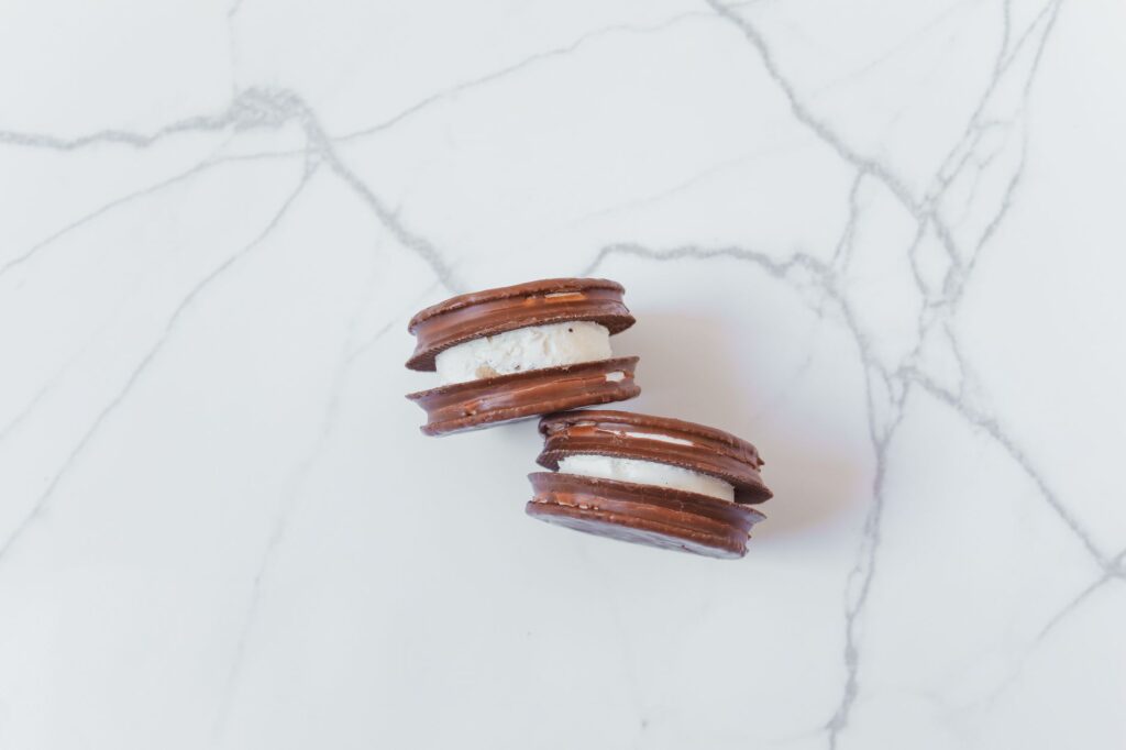 Délicieux biscuits au chocolat avec crème sur un fond en marbre. Idéal pour les amateurs de desserts.