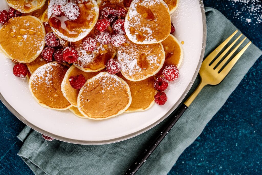 Gros plan sur des pancakes avec des framboises et du sirop, parfait pour le petit déjeuner.