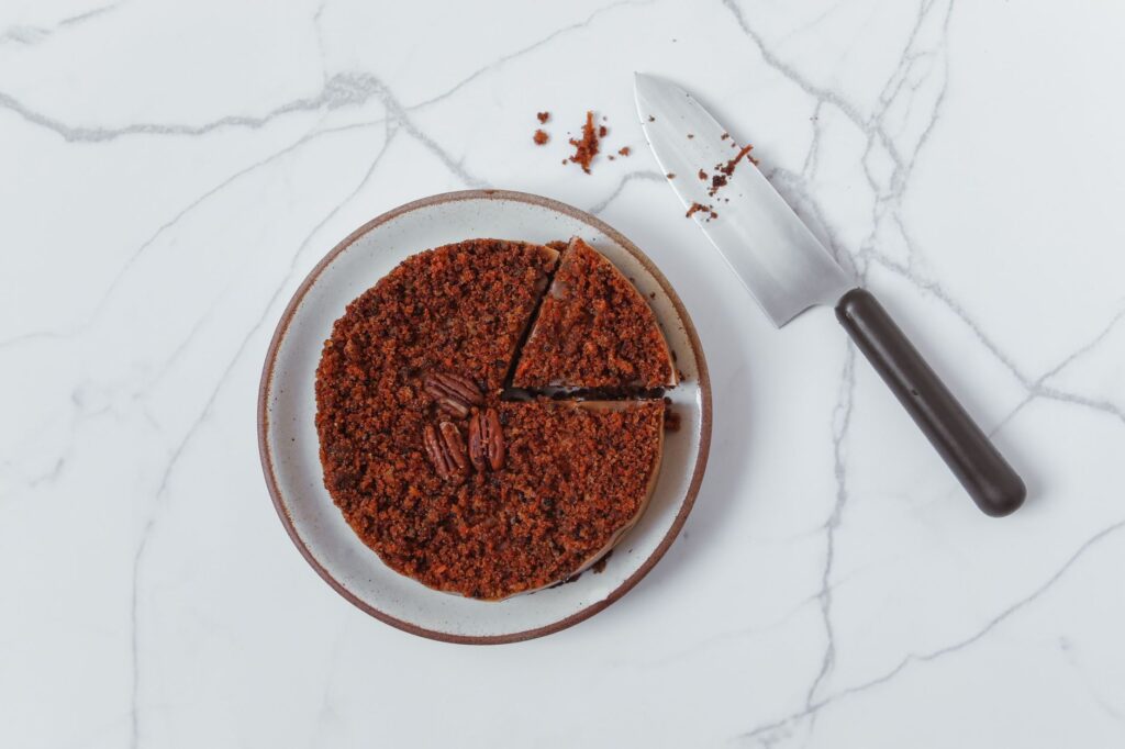 Délicieuse tranche de gâteau au chocolat sur une assiette blanche avec des noix de pécan, mise en scène sur une surface en marbre.