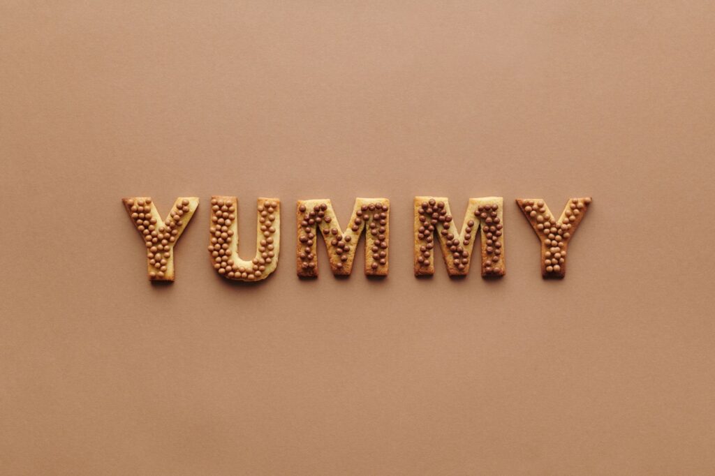 Affichage artistique de biscuits en lettres épelant 'Délicieux' sur un fond brun uni, parfait pour des projets liés à la nourriture.