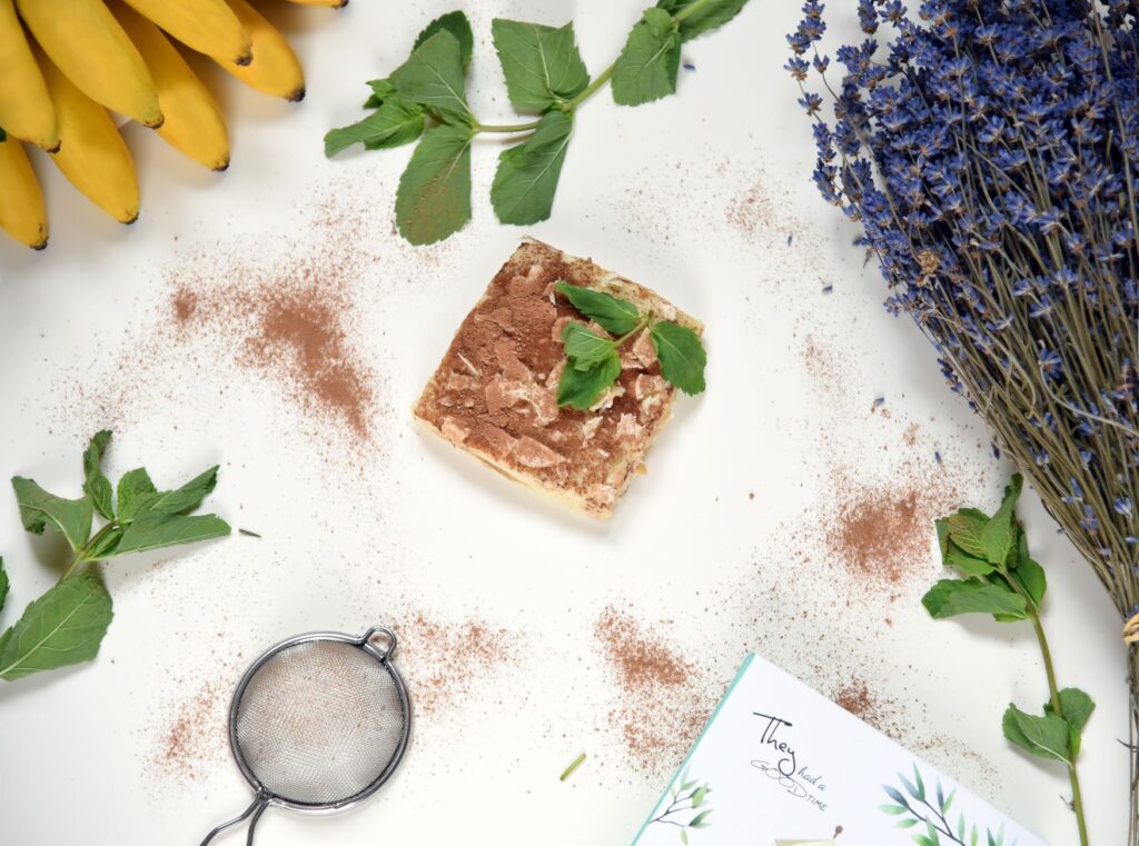 Composition artistique d'un dessert avec des bananes, de la lavande, des feuilles de menthe et de la poudre de cacao.