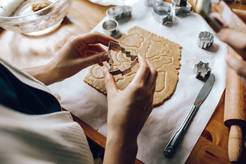 Personne utilisant des emporte-pièces sur de la pâte pour des pâtisseries festives.