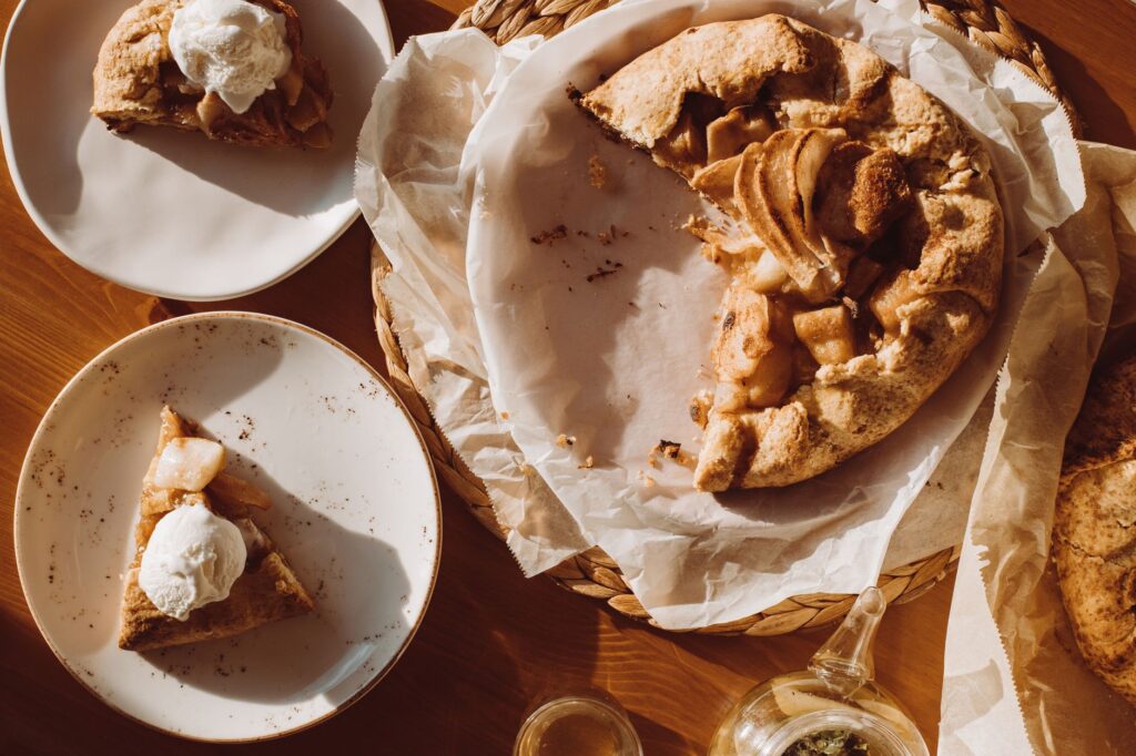 Galette rustique aux pommes avec glace vanille sur des assiettes sous un soleil chaud.