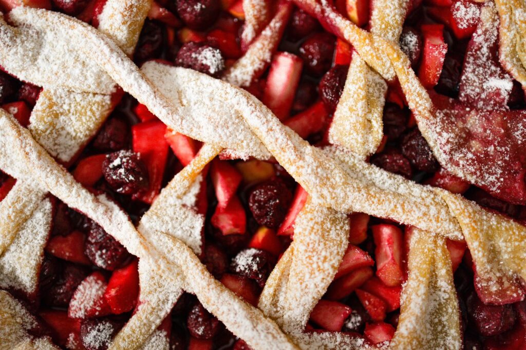 Gros plan d'une tarte aux cerises et aux pommes avec une croûte en treillis saupoudrée de sucre glace.