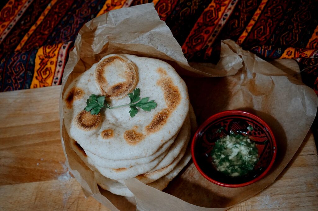 Pain naan indien fraîchement cuit servi avec une sauce à tremper savoureuse, capturé dans un cadre confortable.