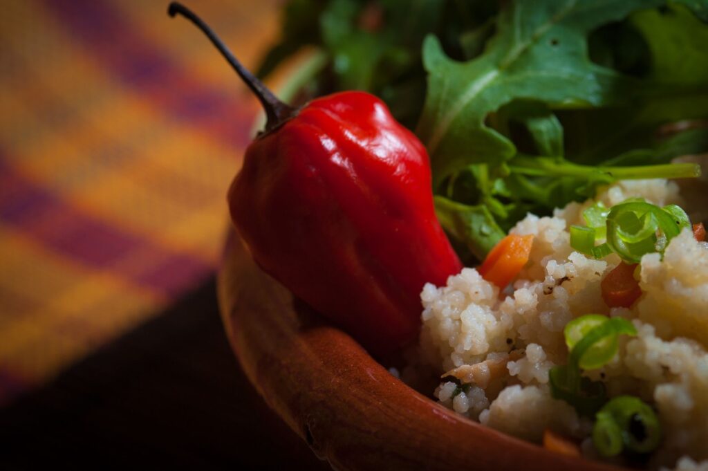 Un bol de couscous épicé garni de poivron rouge frais et de roquette, créant un plat vibrant et sain.