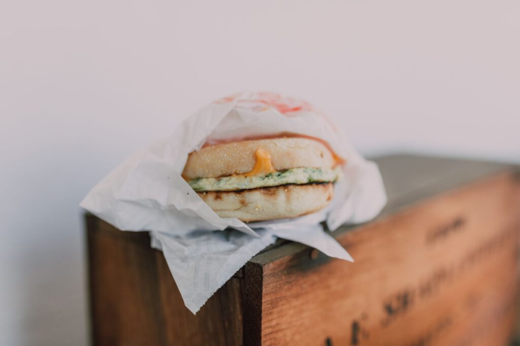 Gros plan sur un délicieux sandwich de petit déjeuner avec du fromage et un œuf sur une boîte en bois.