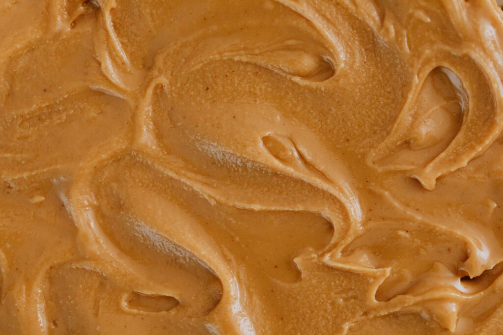 Texture de pâte à tartiner lisse et crémeuse avec des tourbillons, parfaite pour des thèmes alimentaires et culinaires.