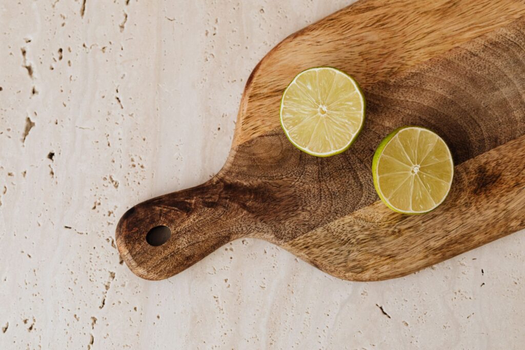 Vue de dessus des moitiés de citron vert sur une planche à découper en bois texturée. Parfait pour des thèmes culinaires.
