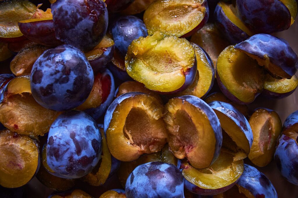 Gros plan vibrant de prunes violettes mûres coupées en deux, mettant en valeur leur texture juteuse et leur couleur riche.