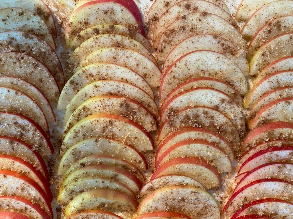 Gros plan sur des tranches de pommes saupoudrées de cannelle et de sucre, parfaites pour la pâtisserie.