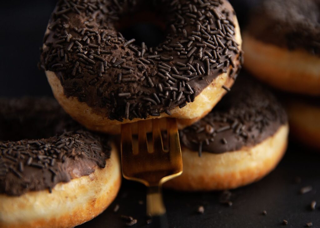 Donut chocolat savoureux avec des vermicelles sur une fourchette dorée, parfait pour la photographie culinaire.