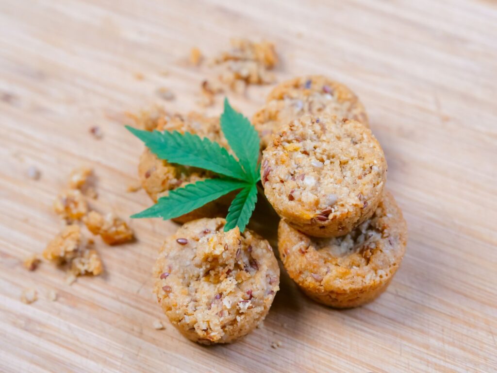 Pile de muffins infusés au cannabis avec une feuille de cannabis sur une surface en bois. Idéal pour des concepts de culture du cannabis.