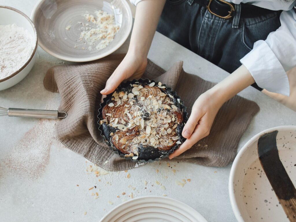 Vue du dessus d'une femme tenant un gâteau aux amandes fraîchement cuit dans sa cuisine.