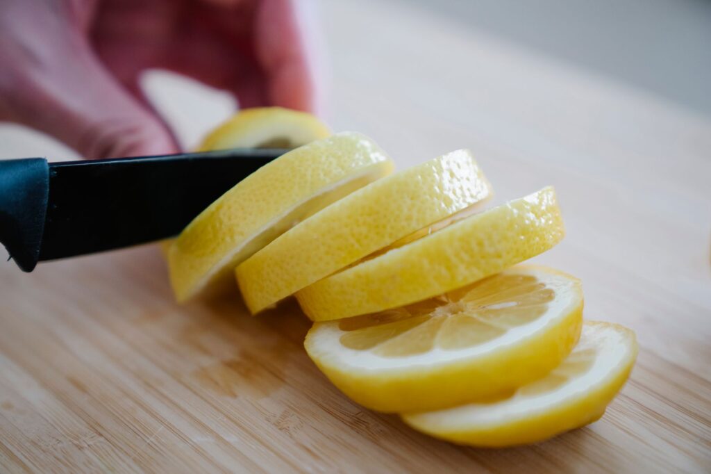 Gros plan d'un citron frais en cours de tranchage avec un couteau sur une surface en bois.