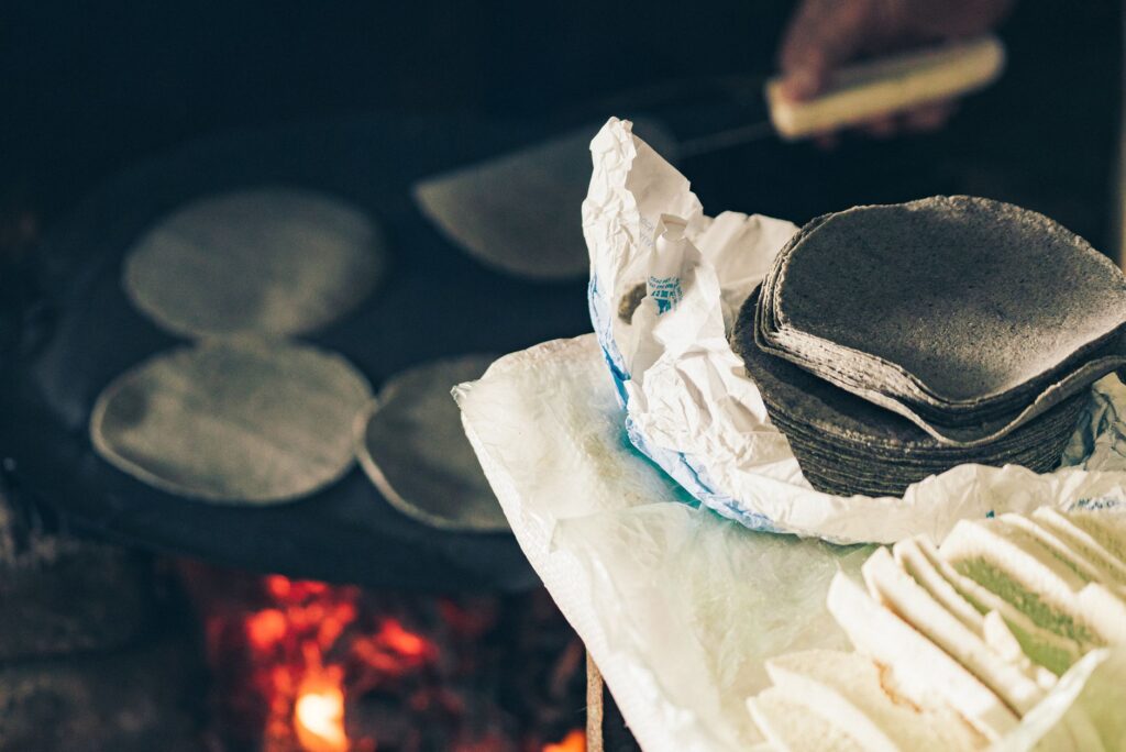 Gros plan sur des tortillas artisanales cuites à feu ouvert, illustrant la tradition culinaire rustique mexicaine.