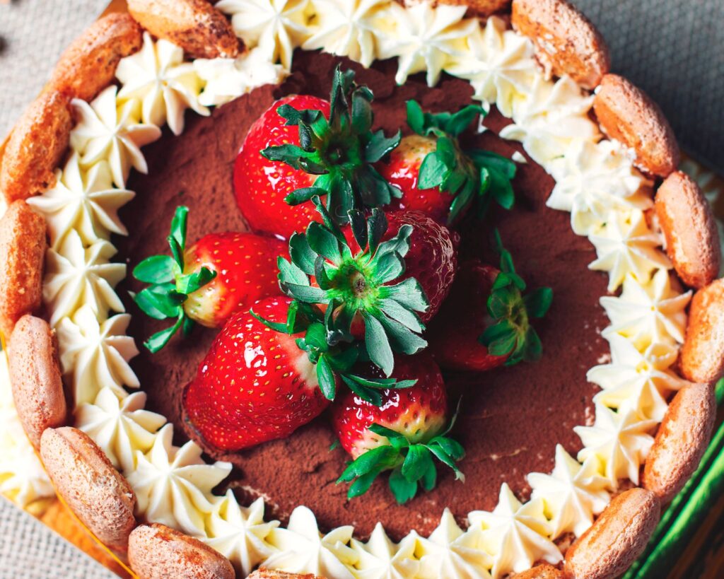 Vue de dessus d'un gâteau au chocolat décoré de fraises fraîches et de crème fouettée, créant un dessert délicieux.