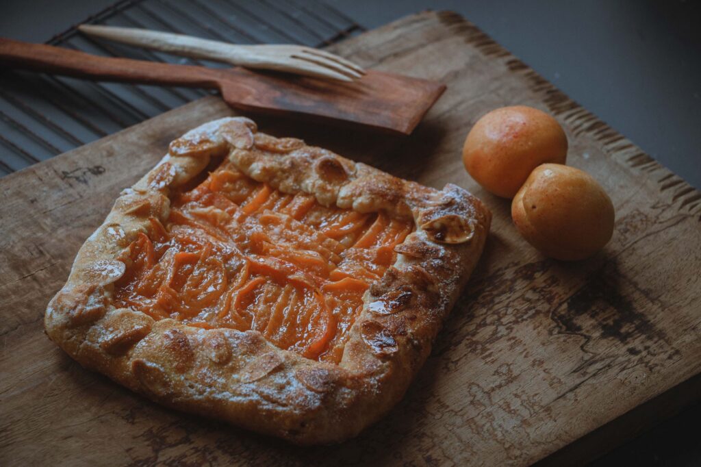 Savoureuse galette d'abricot faite maison sur une planche en bois rustique, parfaite pour les amateurs de desserts.