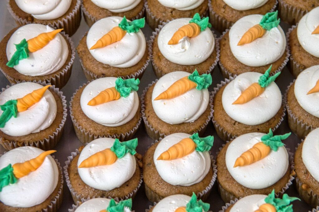 Rangées de cupcakes aux carottes avec un glaçage au fromage à la crème, parfaits pour les amateurs de desserts.