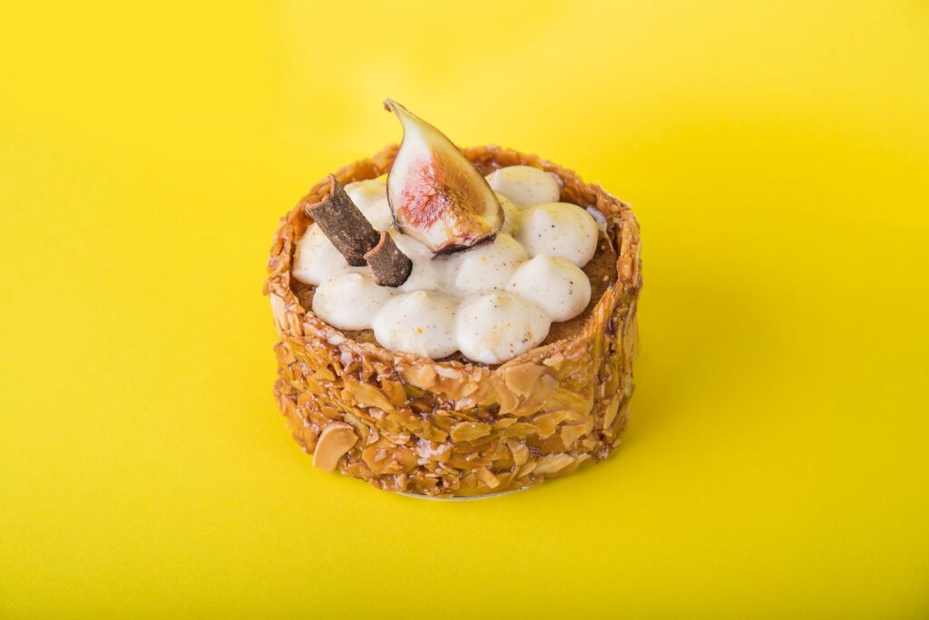 Élevez votre photographie de desserts avec cette exquisite tarte aux figues, parfaitement stylée sur un fond jaune vibrant.