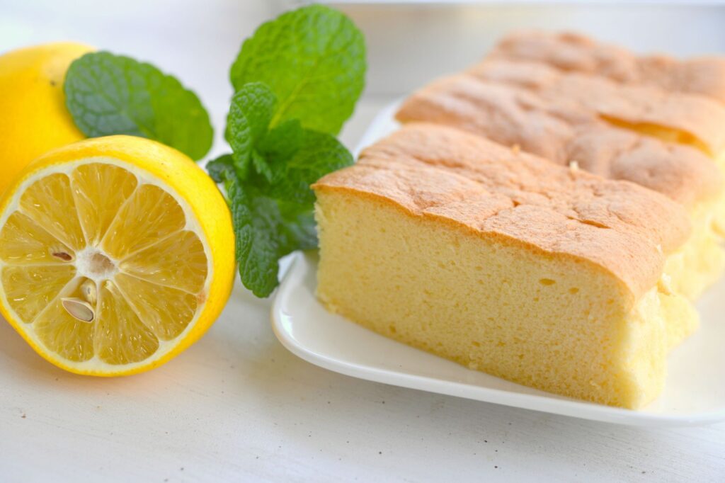 Gâteau éponge au citron tranché avec des feuilles de menthe fraîches sur une assiette blanche.