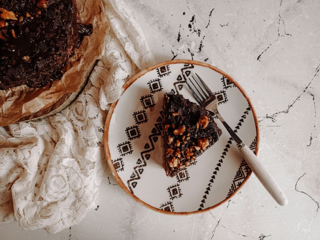 Délicieuse tranche de gâteau au chocolat avec des noix sur une assiette décorative, vue d'en haut.